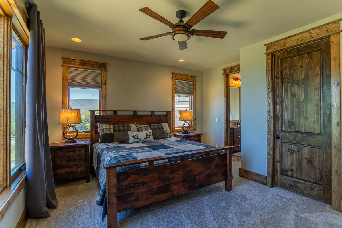 A serene bedroom with a plush bed, nightstands topped with lamps, windows letting in natural light, and a door leading to another space. The room exudes comfort and relaxation, aligning with the restful haven described in the section.